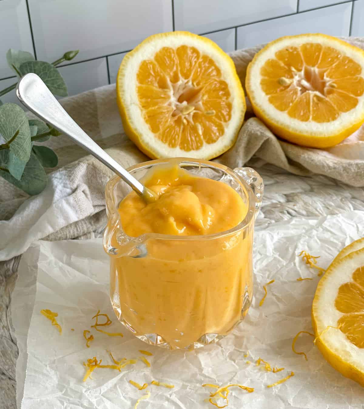 Lemon curd in a glass jug with slices of lemons 
