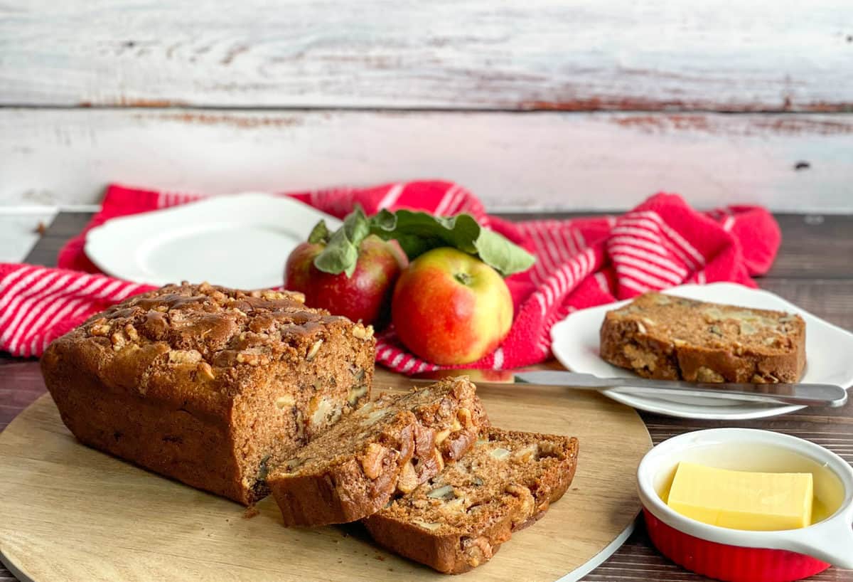 Apple and walnut loaf on a wooden board with fresh apples and butter 