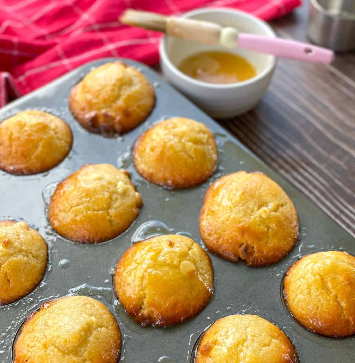 Muffin tray with freshly baked passionfruit muffins smothered in syrup