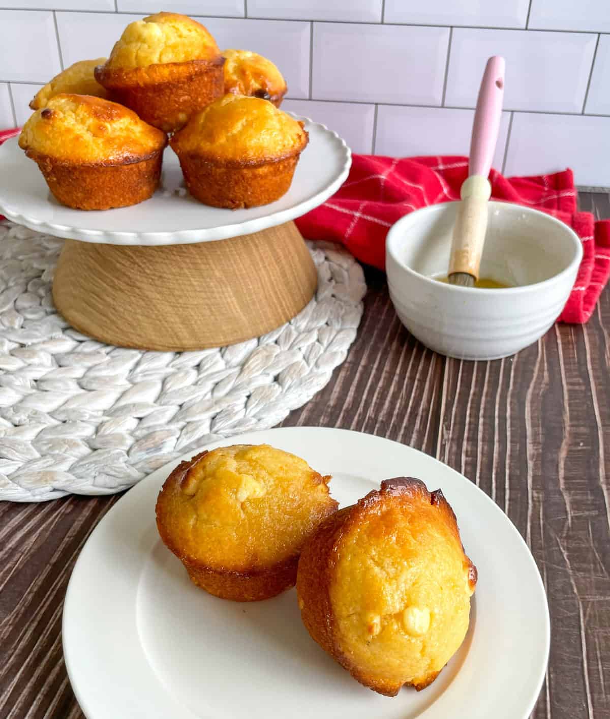 Passionfruit Muffins with bowl of syrup and pastry brush on white plates. 
