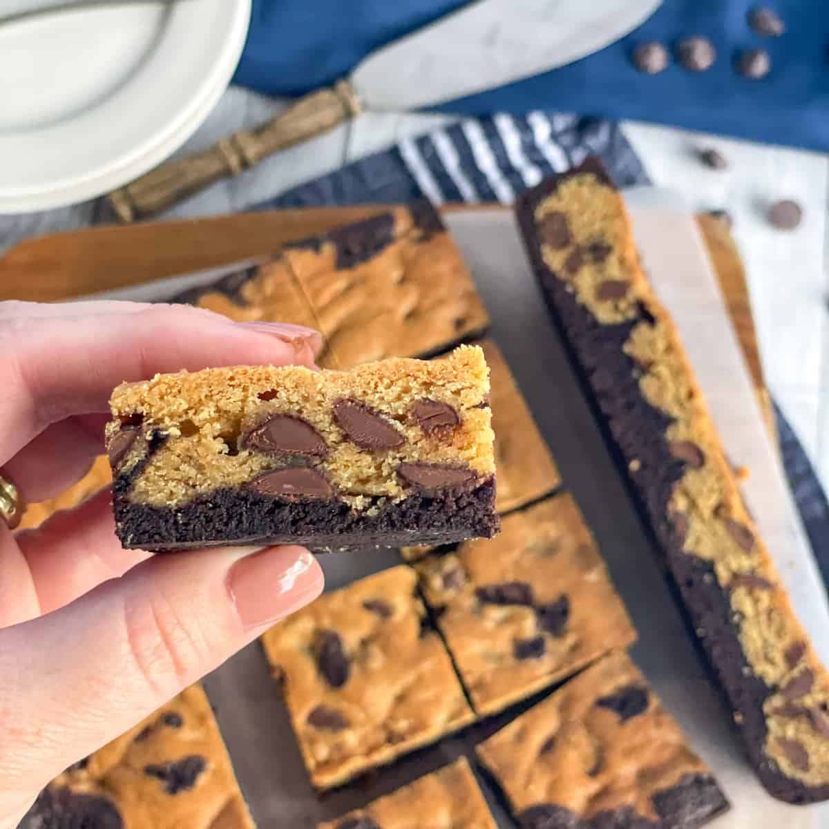 A hand holding a piece of Brookie with the rest of the slice in the background