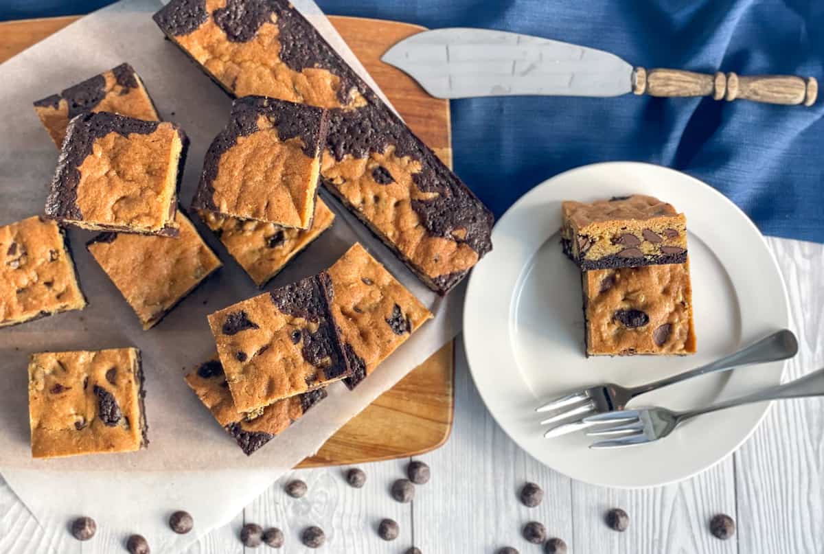 Overhead photograph of sliced brookie, cookie and brownie combined and on a wooden board and a plate