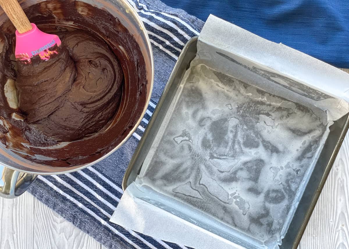 A prepared brownie pan and brownie mixture in a bowl