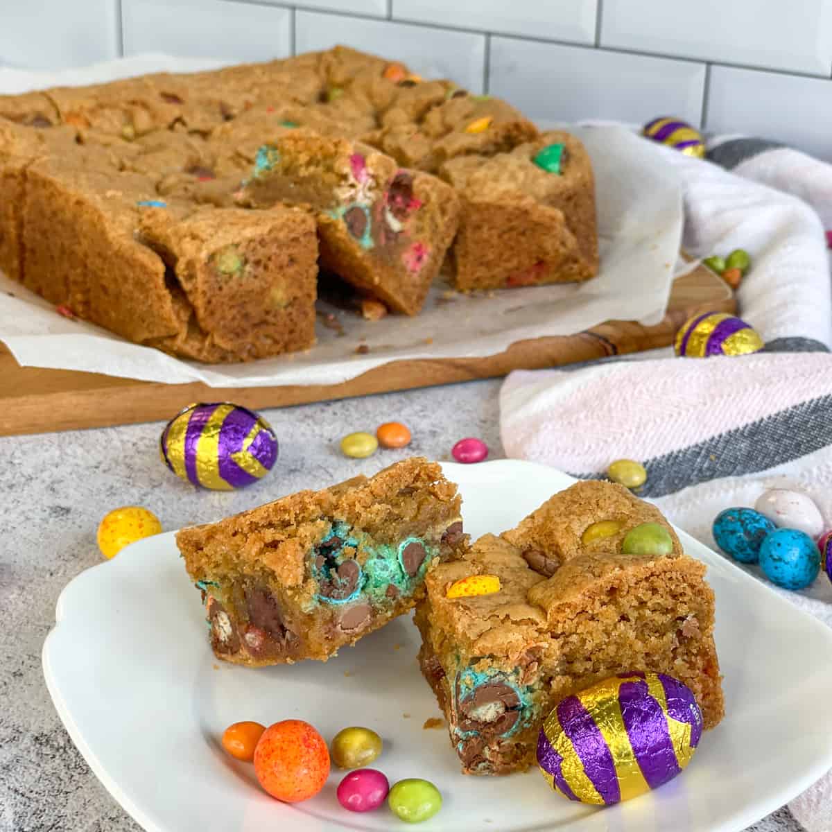 Two pieces of Easter Cookie Slice surrounded by mini easter eggs on a white background
