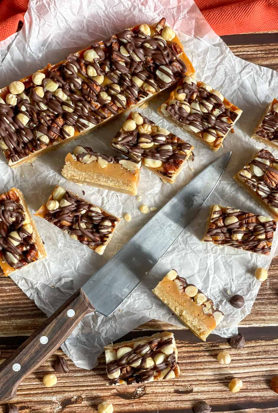 Slices of Caramel Nut Slice, on a baking paper background with a sharp knife 