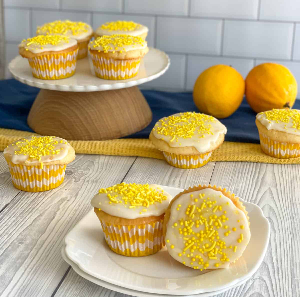 Simple Lemon Cupcakes, on a white plate, cake stand with fresh lemons. 