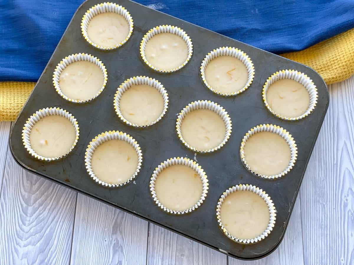 Lemon cupcake batter in a muffin tin with cupcake liners