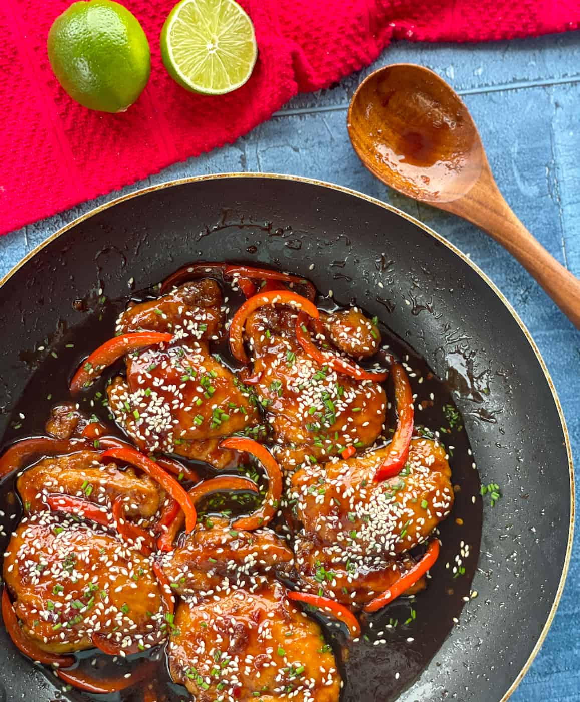 Sticky Asian Chicken in a frying pan with limes