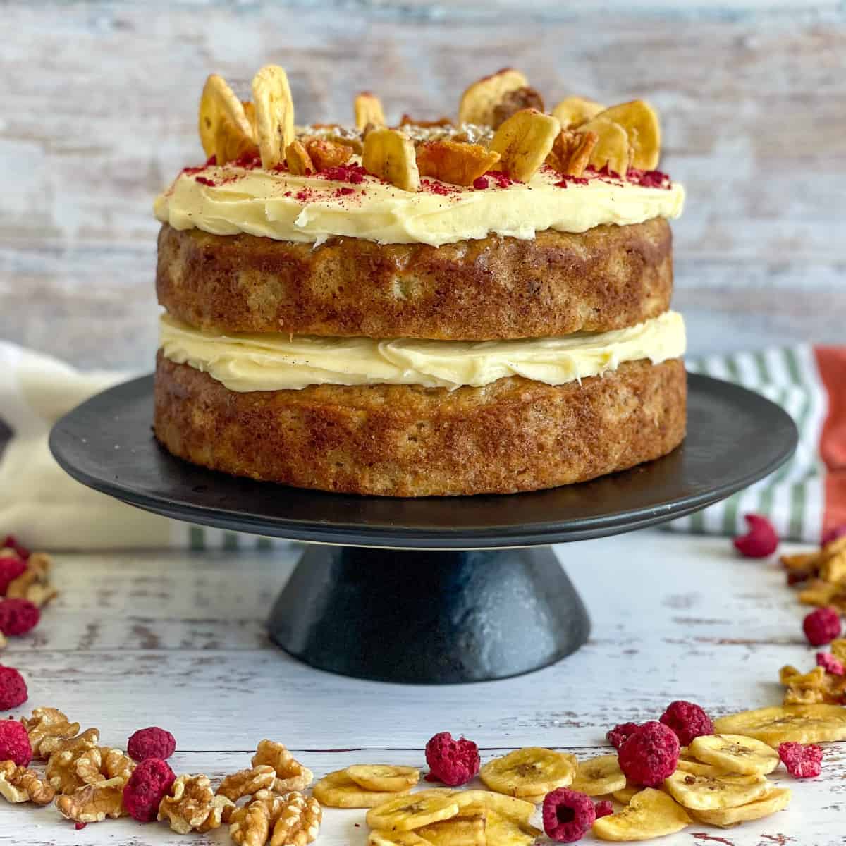 Hummingbird Cake with two layers, frosted with cream cheese icing on a black cake stand.