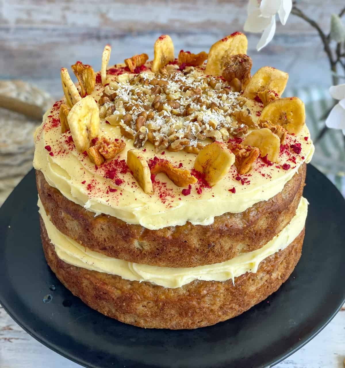 Completed Hummingbird Cake with Cream Cheese frosting and decorated with nuts and banana chips