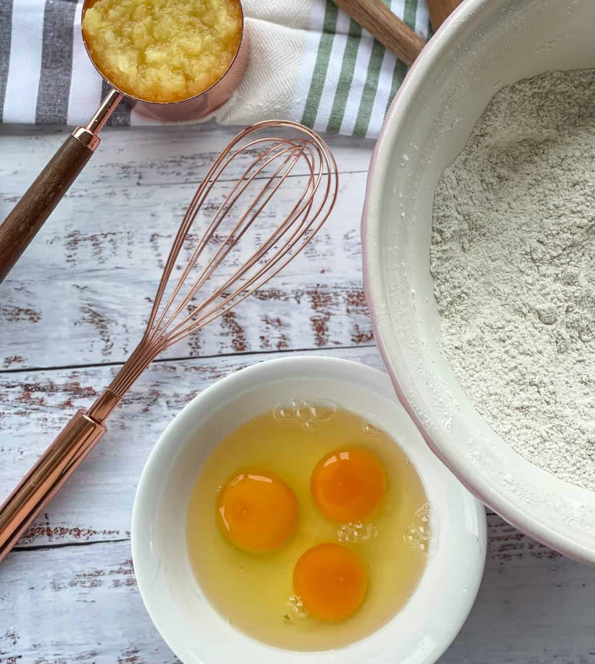 3 eggs in a bowl and a rose gold whisk, ready to be added to hummingbird cake 