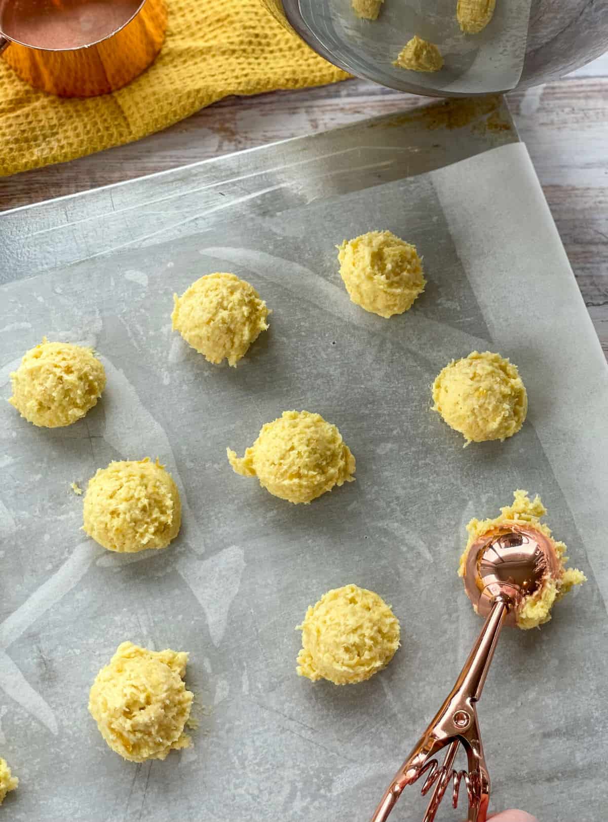 using a cookie scoop to dollop cookie dough mixture onto a prepared tray