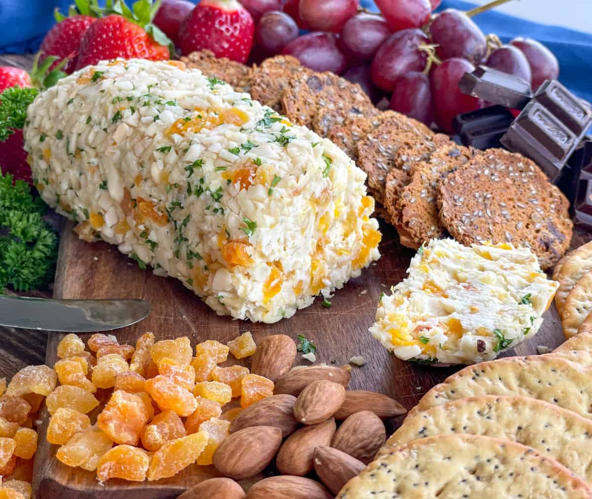 Apricot Almond Cheese Log on a platter with fruits, crackers and chocolate 