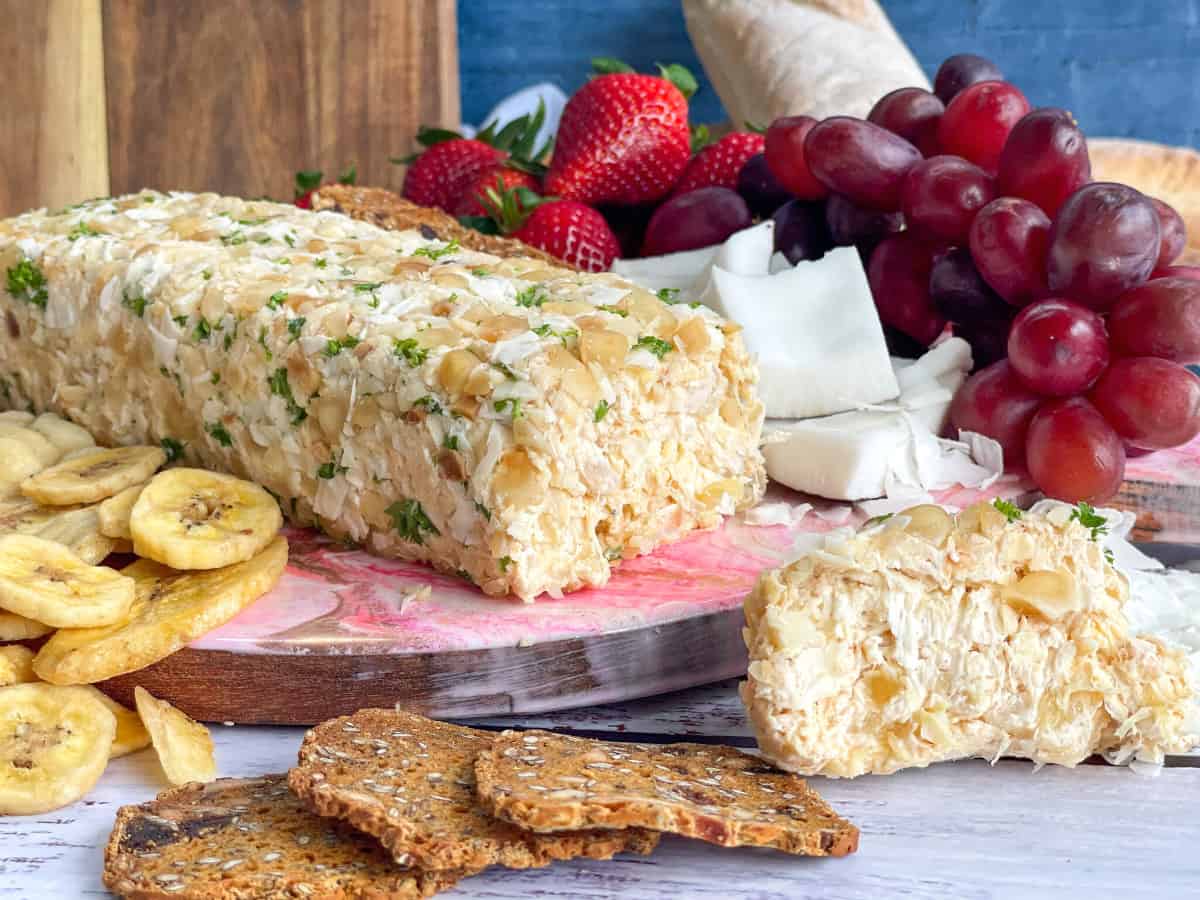Pineapple Macadamia and Coconut Cheese Log on a fruit platter with fruits, crackers and dried fruits