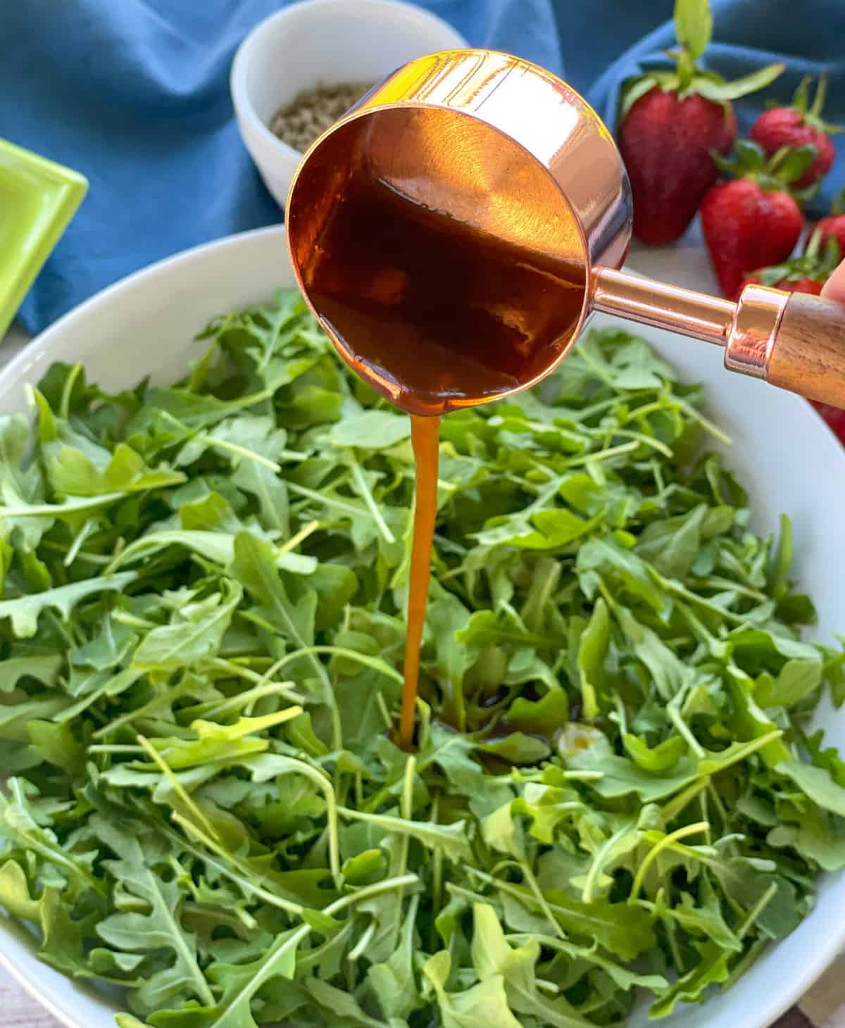 Pouring Balsamic Dressing on Rocket with Rose Gold Measuring Spoon 