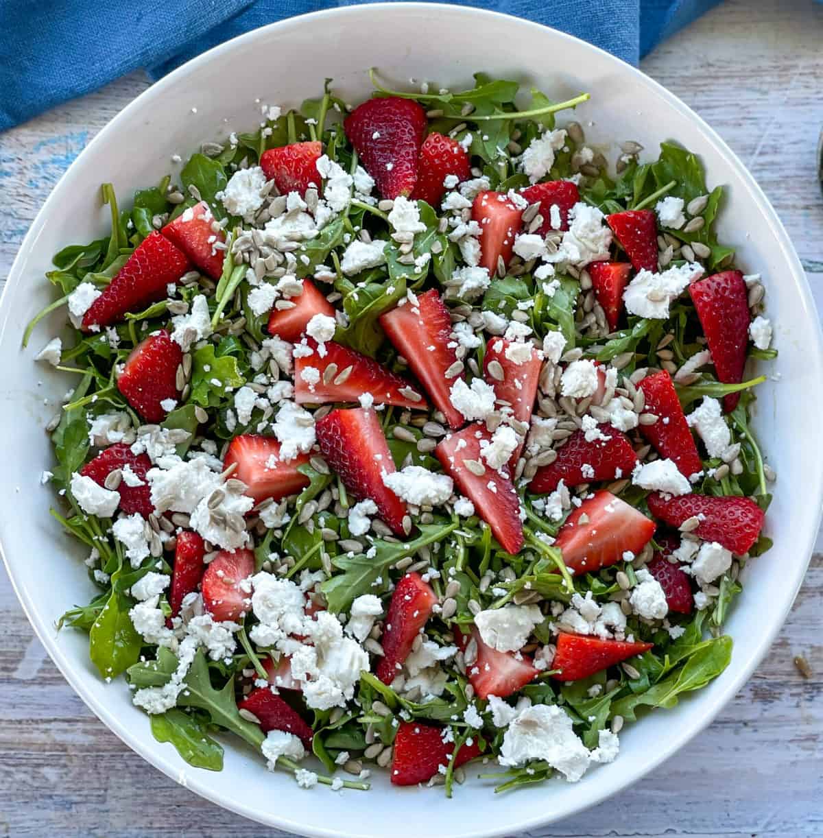 Rocket, Feta, Strawberries and sunflower seeds combined in a large white bowl