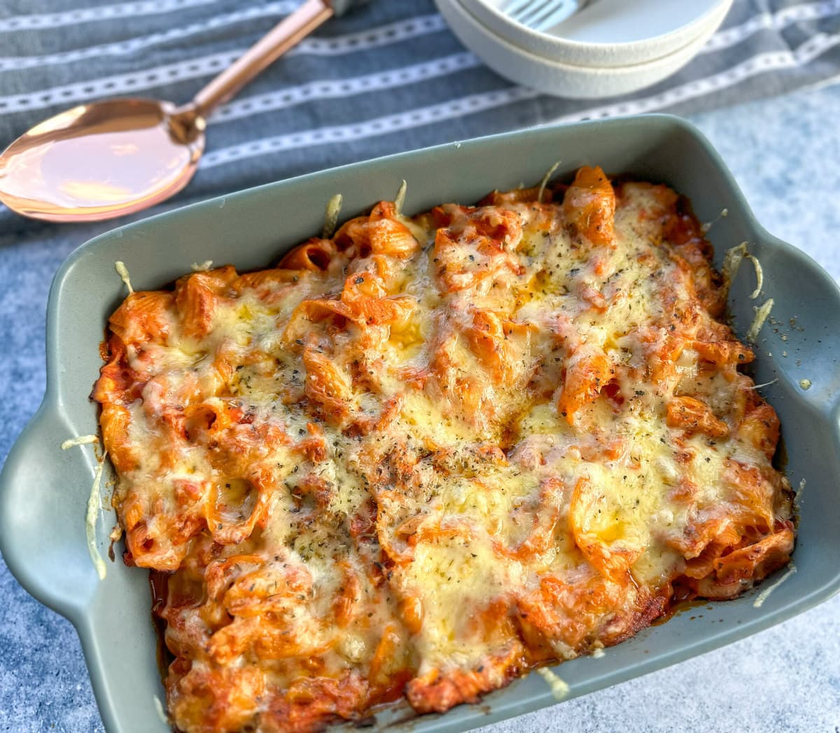 Creamy Tomato Pasta Bake in a green baking dish, covered in melted cheese 
