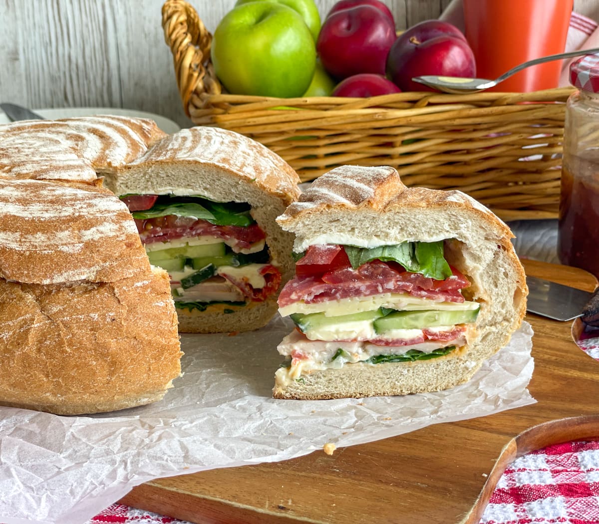 A round loaf filled with layers of fresh salad ingredients, deli meats and cheese, sliced in a cake form