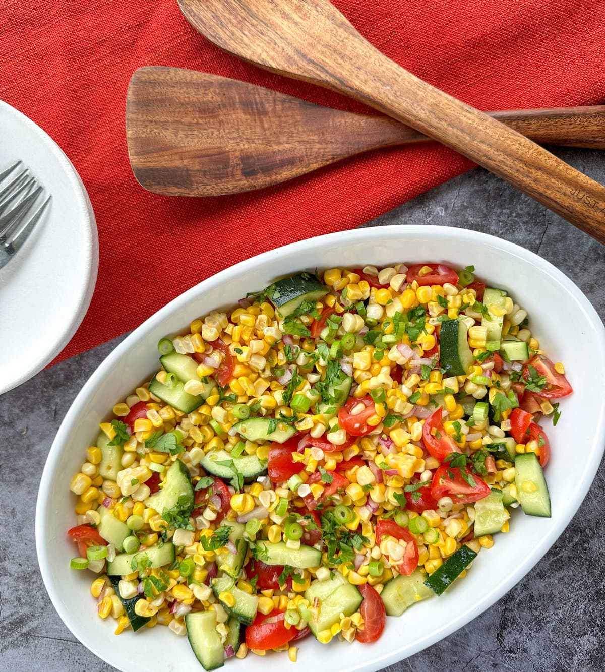 Sweetcorn Salad in a large white bowl with wooden salad utensils 