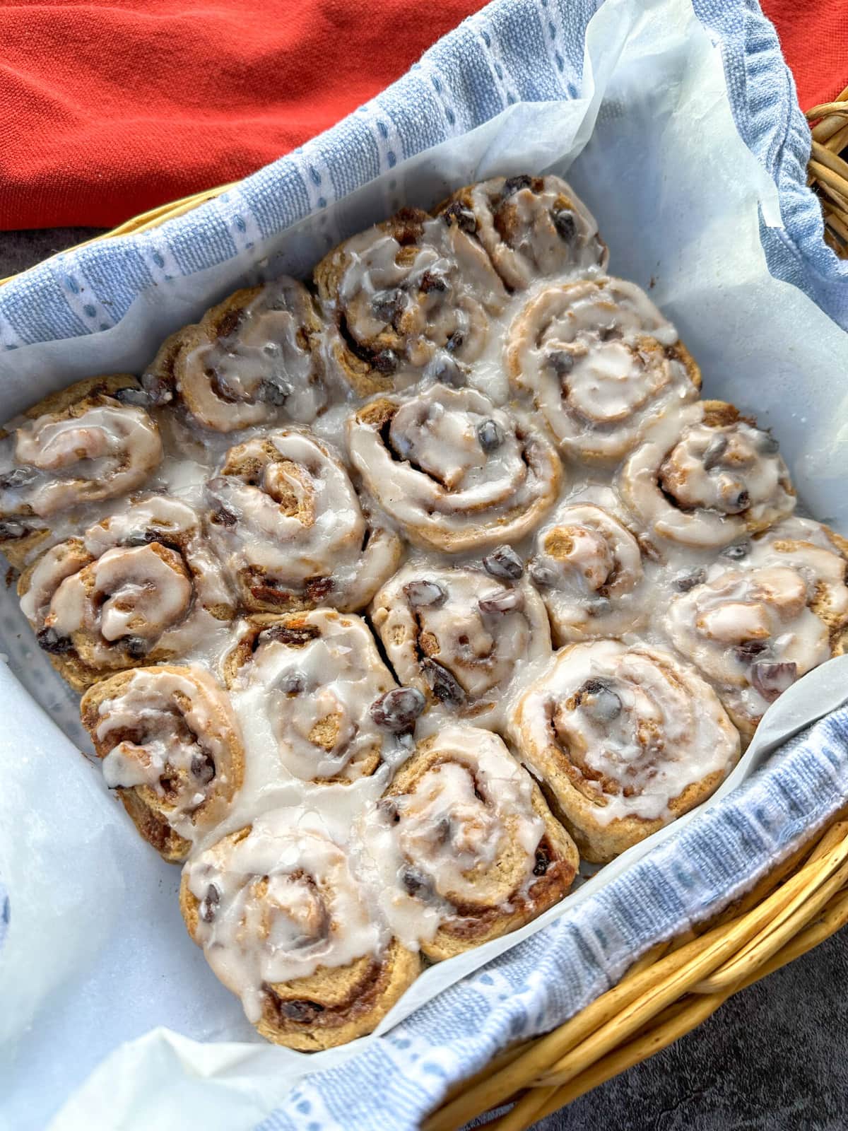 A basket of freshly baked hot cross cinnamon scrolls with a vanilla glaze. 