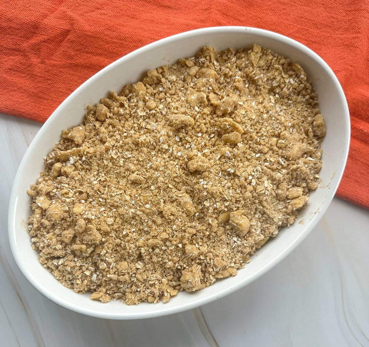 Apple crisp in a white dish before baking 