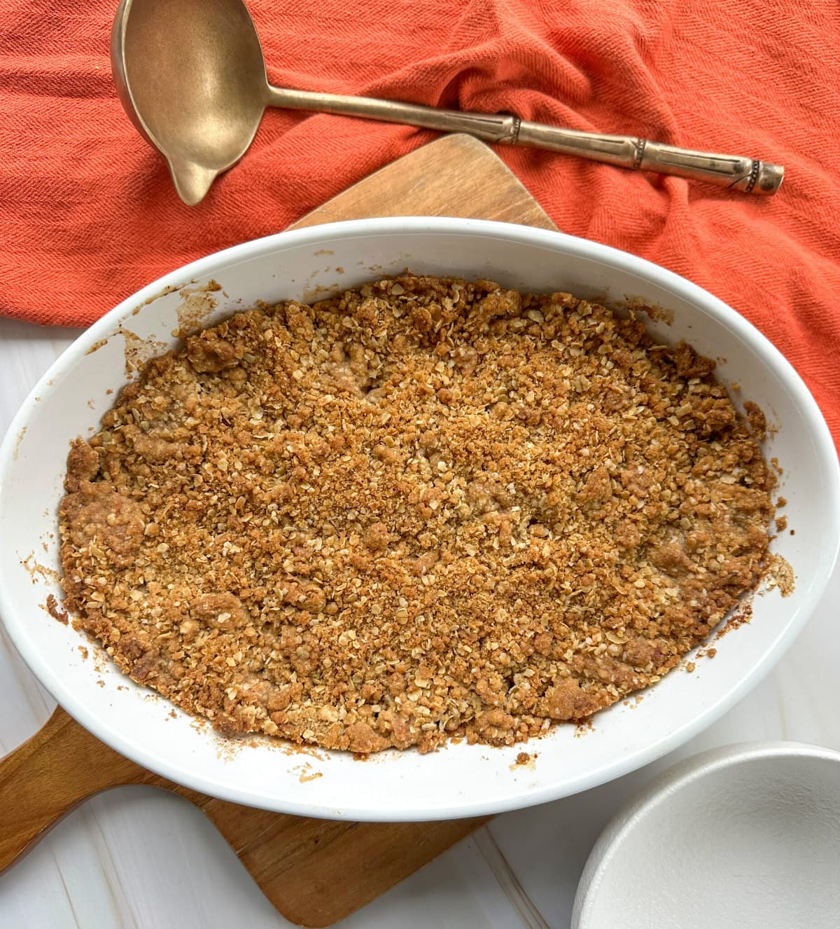 Golden brown baked apple crumble crisp with oats in a white dish 
