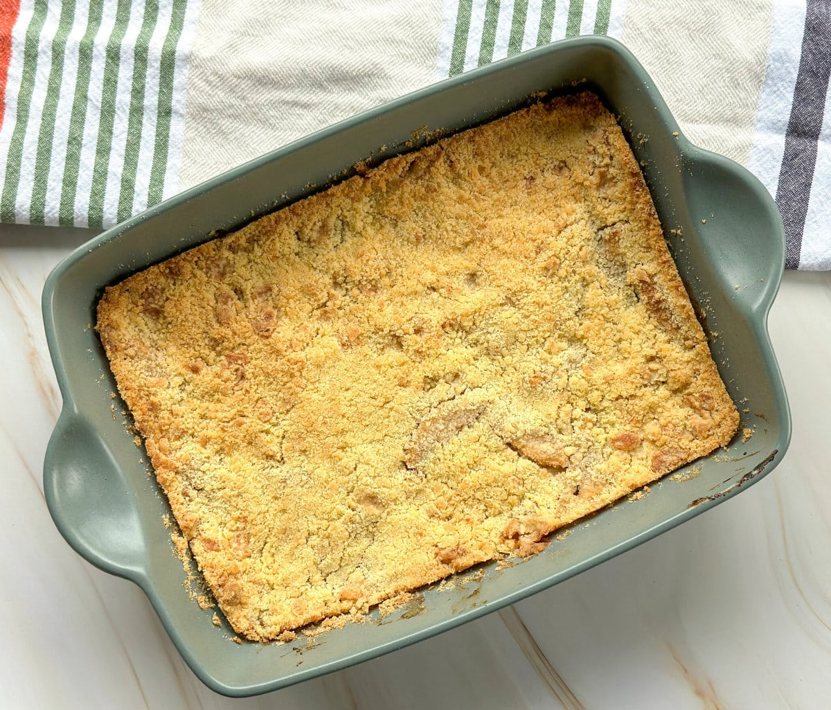 Golden brown apple crumble baked in a green dish