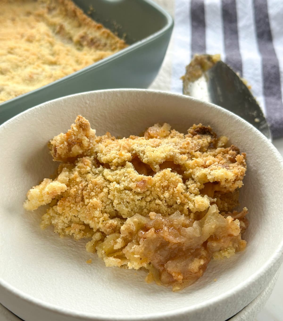 Serving of basic classic apple crumble with apple coated in cinnamon and sugar and a crumble topping