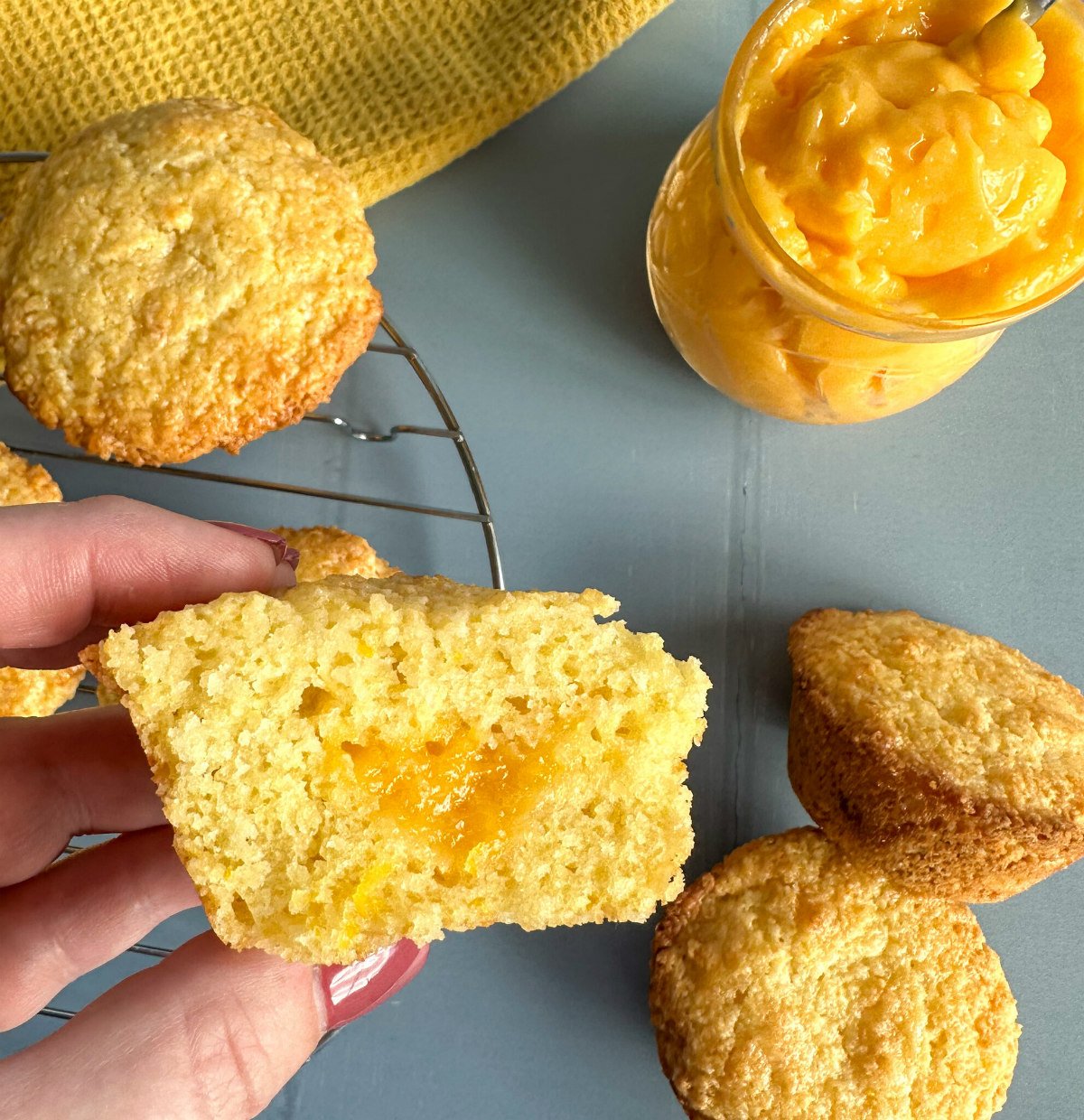 A hand holding a lemon muffin with lemon curd filling