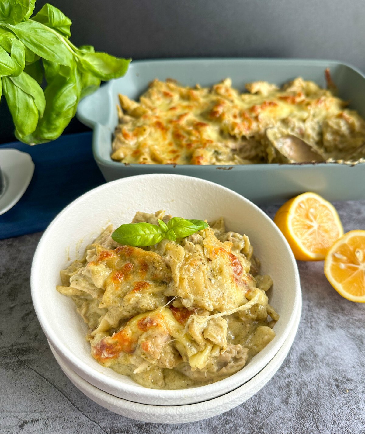 White bowl of slow cooker chicken pesto pasta with lemon and basil