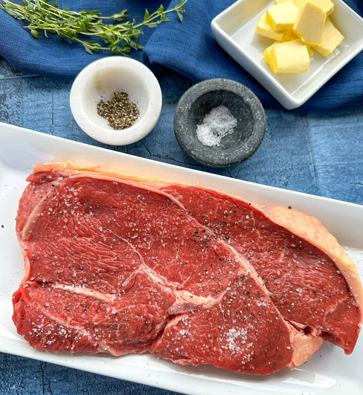 Seasoned rump steak with salt and pepper ready for cooking