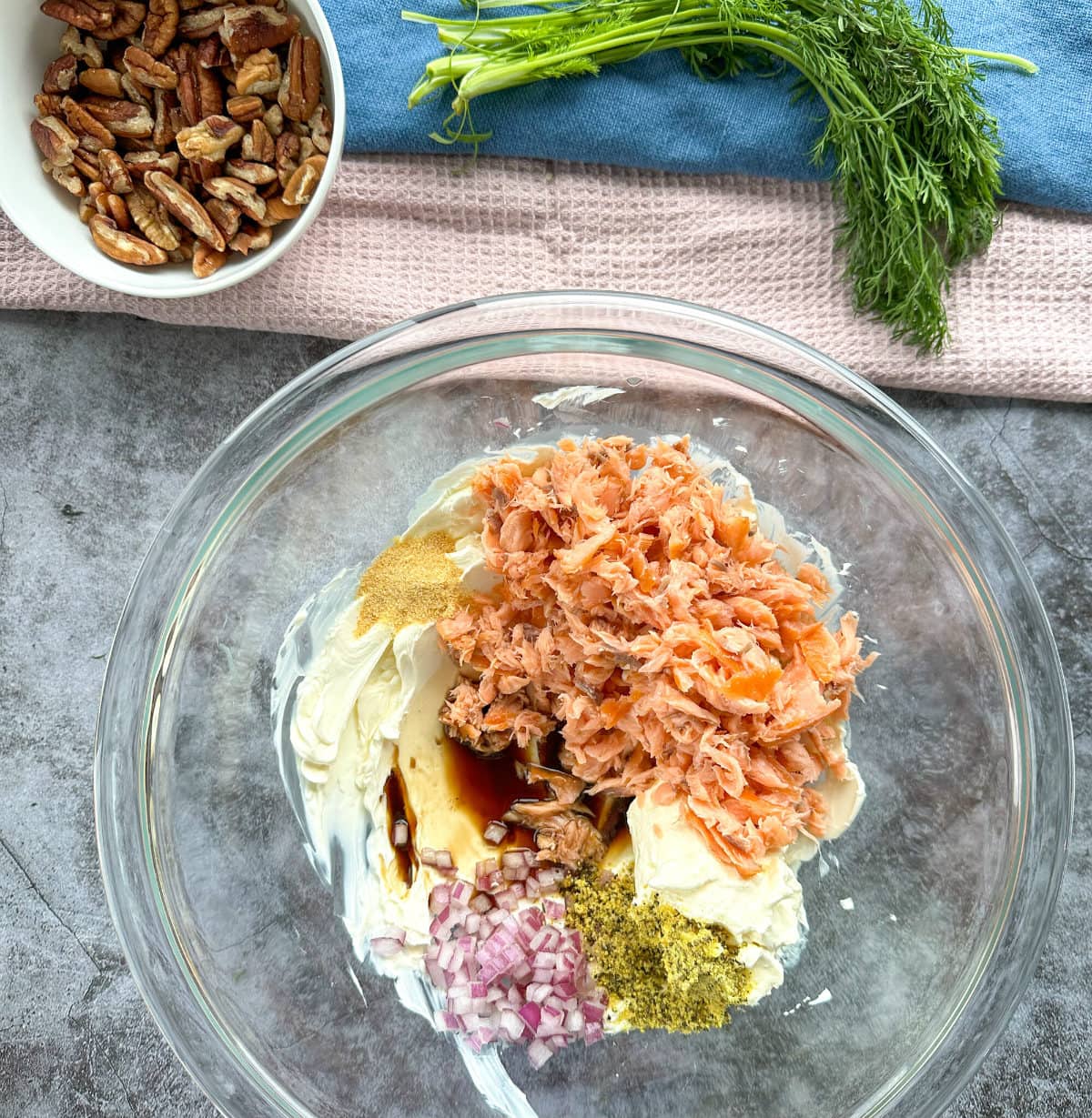 How to make a salmon cheeseball with flaked smoked salmon, mixed with other ingredients in a clear glass bowl