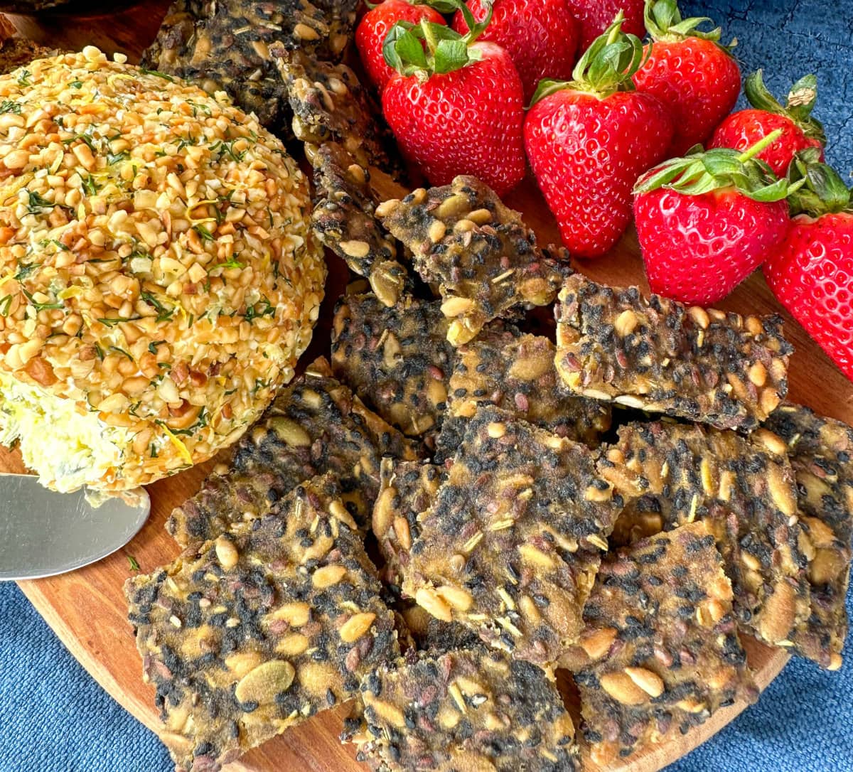 Wooden platter with seeded crackers homemade and a cheeseplatter with strawberries