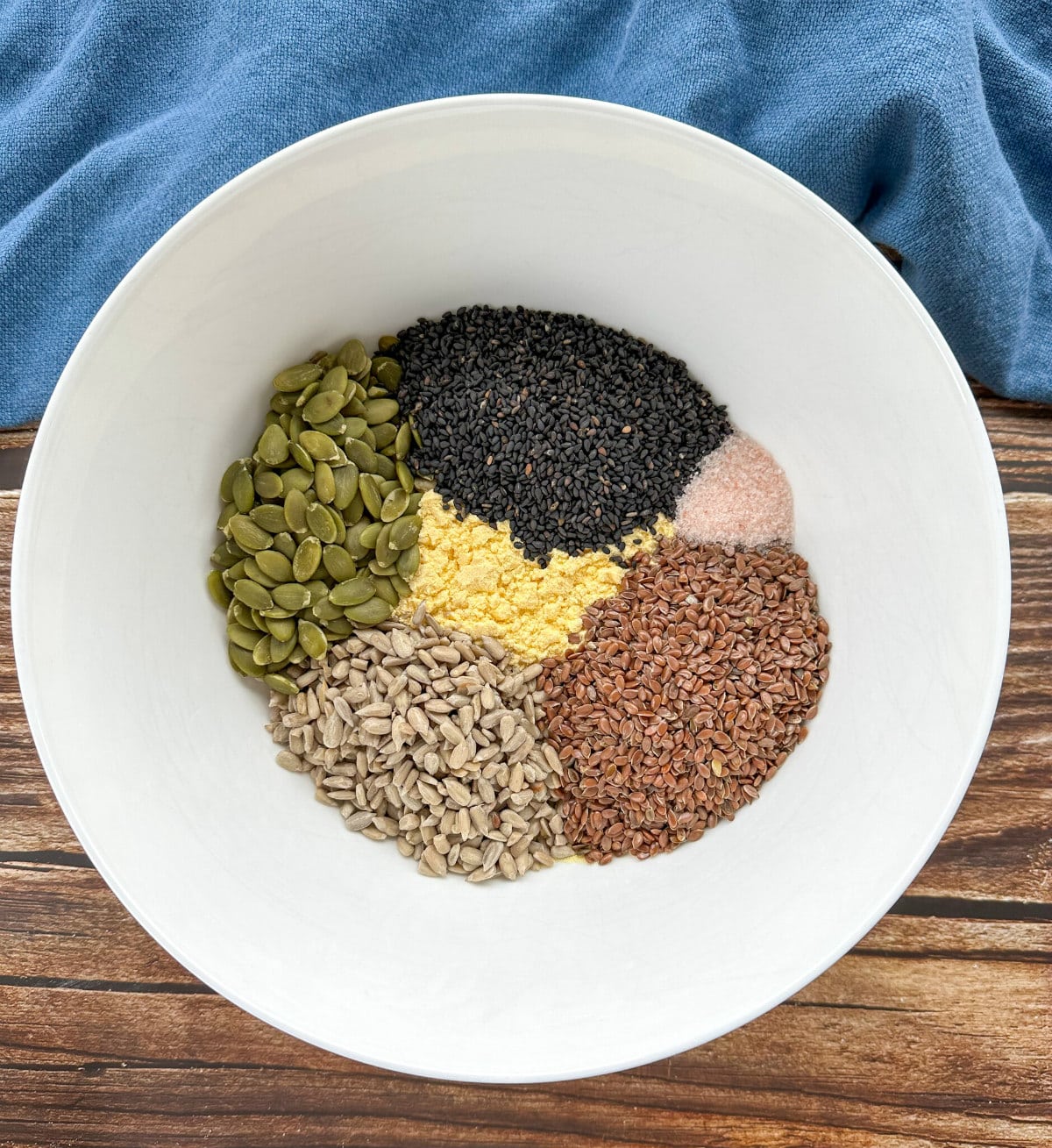 A white bowl with 4 different seeds, pink salt and cornmeal