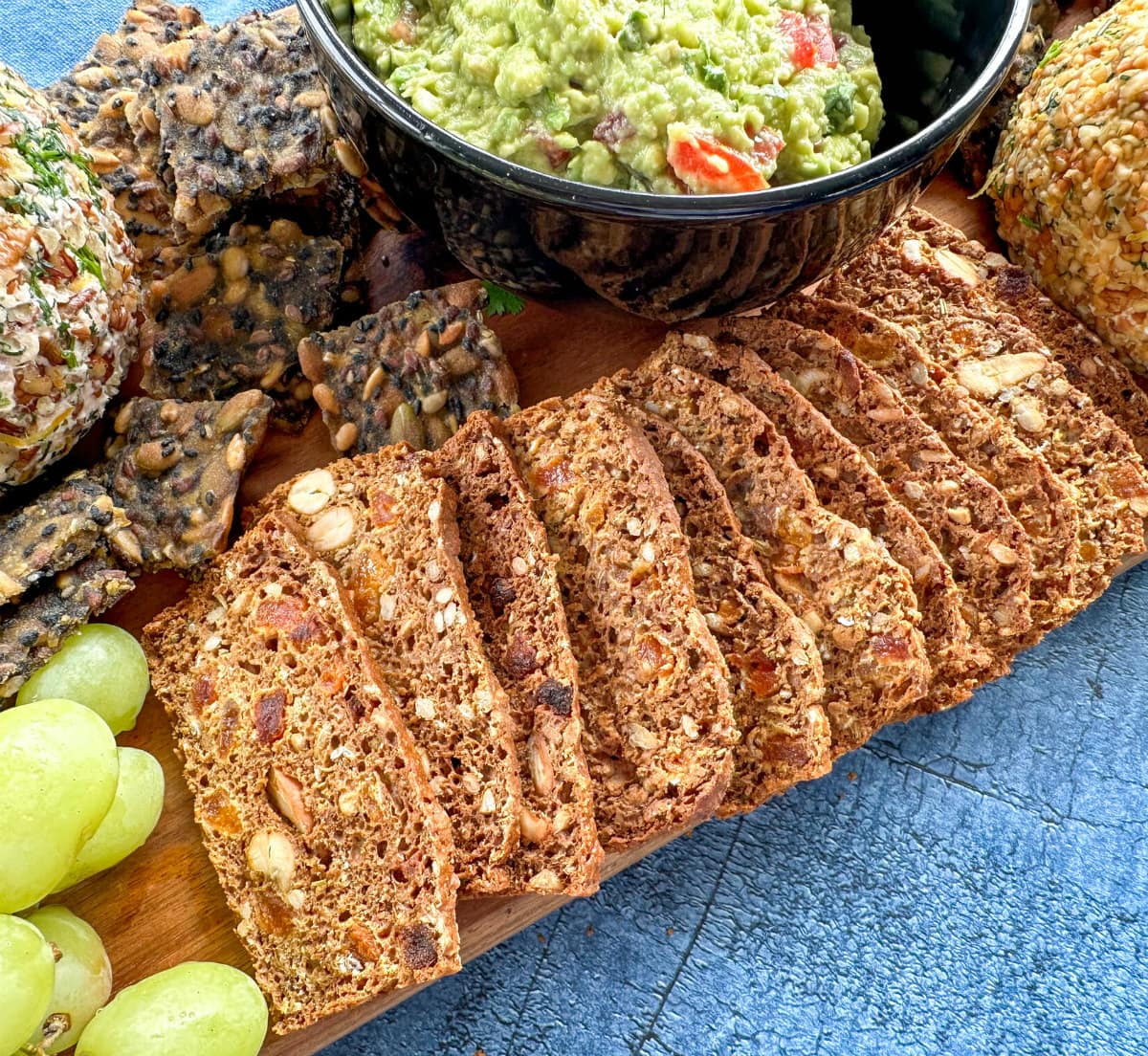 Gourmet crackers on a cheese platter with guacamole and grapes 