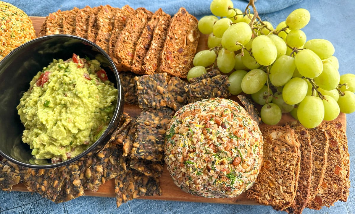 Cheese Platter with homemade guacamole, seeded crackers, gourmet crackers and a salmon cheeseball and grapes