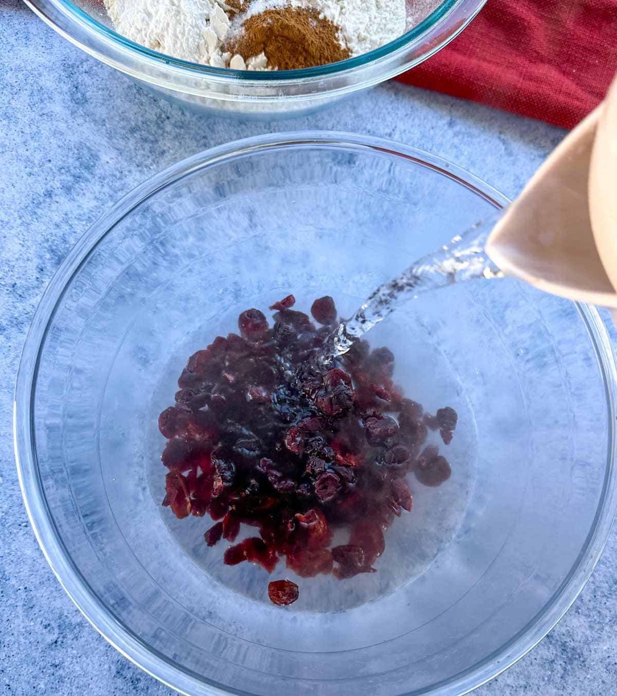 Pouring boiling water over the dried cranberries to soften them before baking