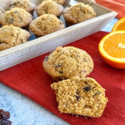 Orange and cranberry muffins on a red background with orange slices