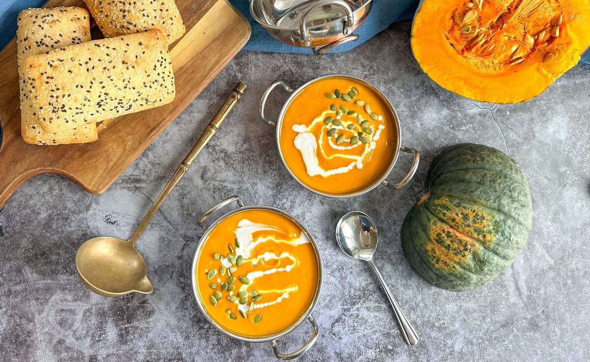 Thai Pumpkin Soup in bowls with a ladle and soup spoon