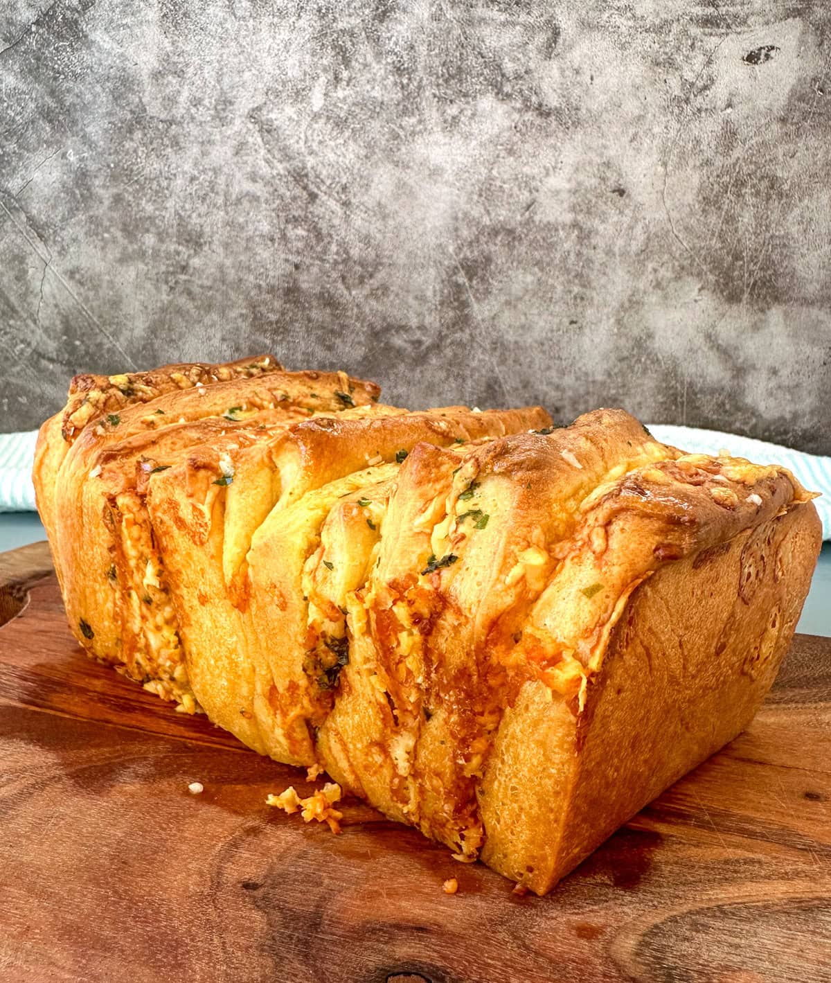 Golden brown freshly baked pull apart loaf on a wooden chopping board