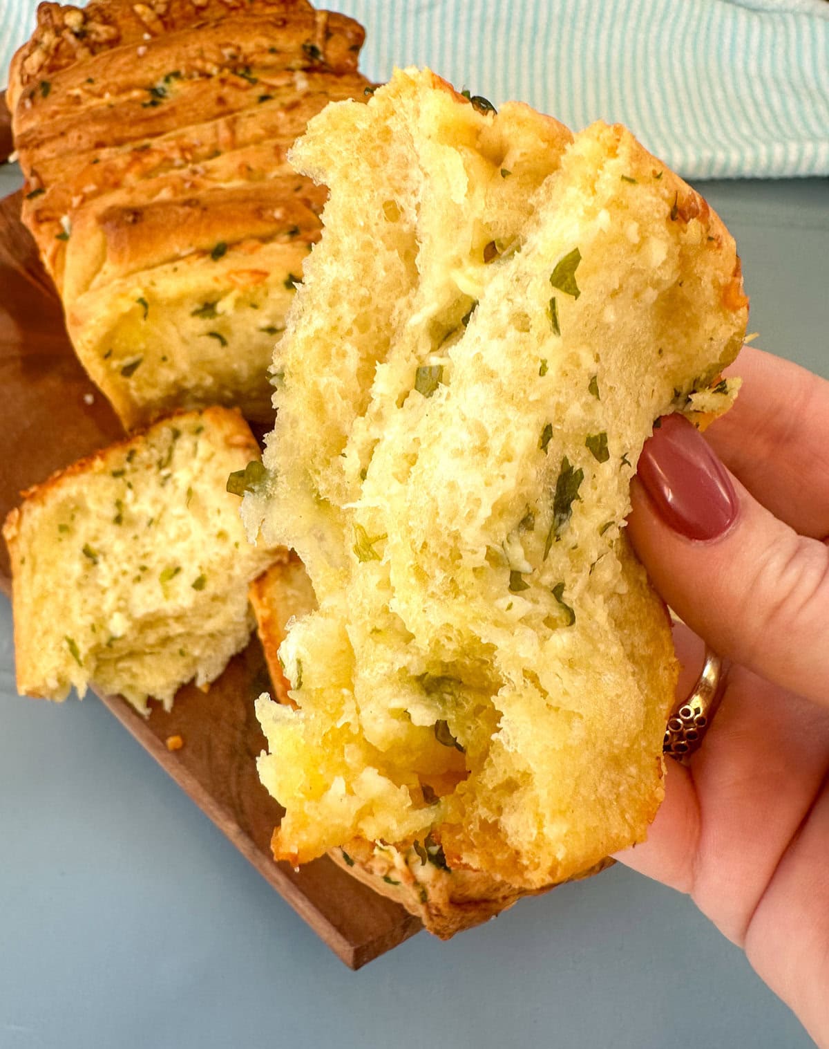 Hand holding fresh pull apart garlic loaf 