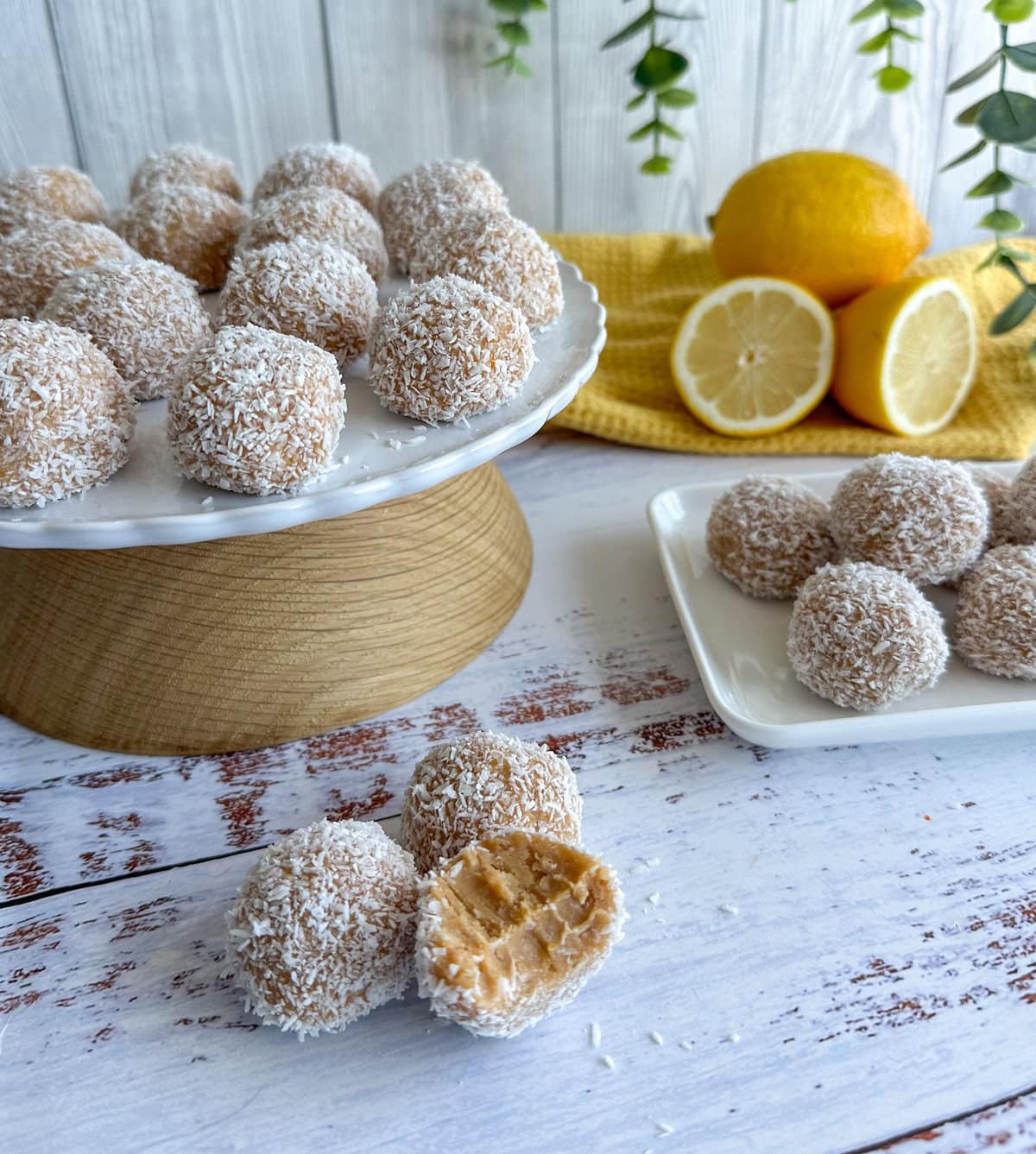 Lemon and Coconut Truffles on plates, made with biscuits, condensed milk and fresh lemons. Sweet treat, balls rolled in coconut with a bite taken out.