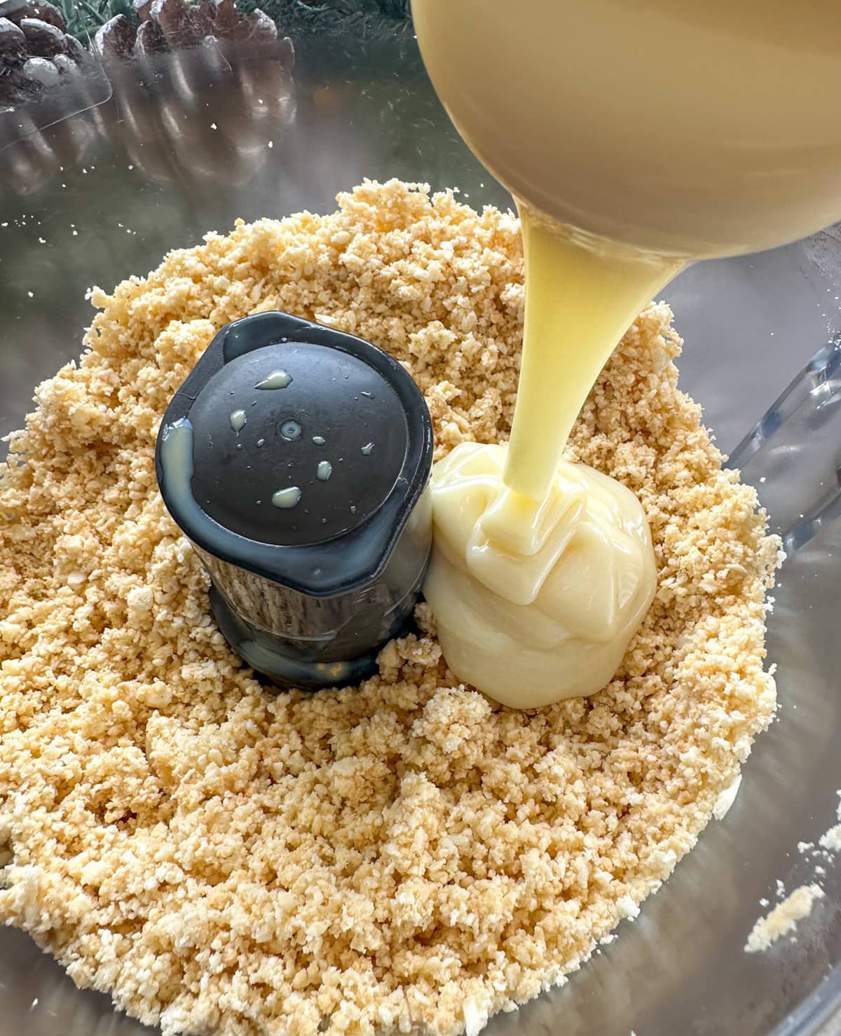 Condensed milk being poured into crushed Tim Tams 