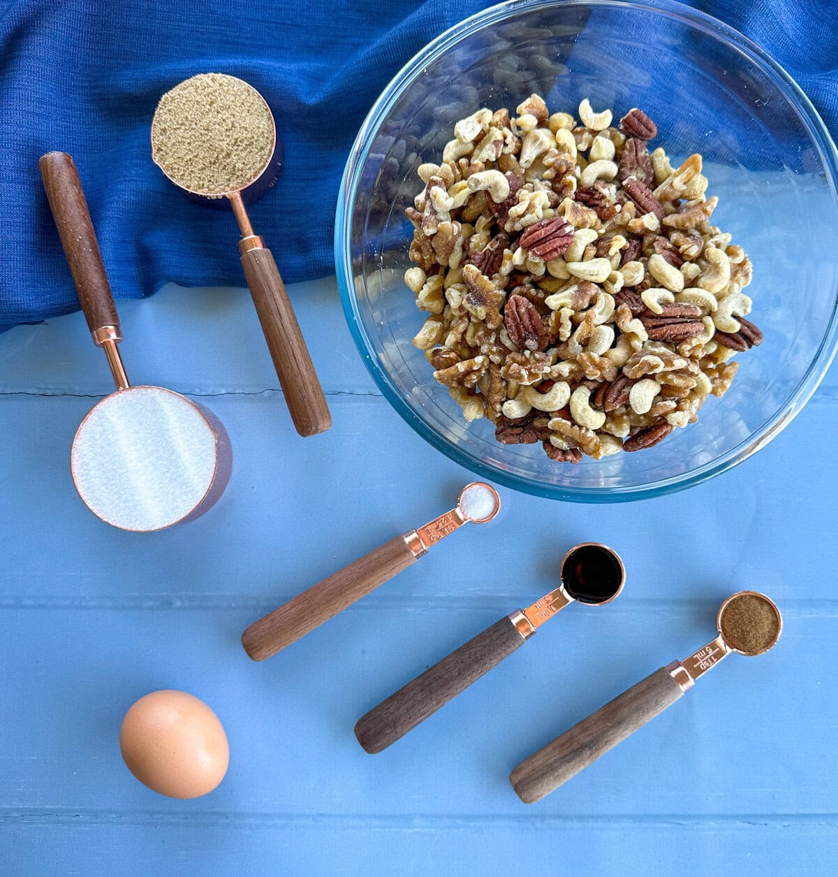 Ingredients laid out on a blue background, for candied nuts, see recipe card for full details. 