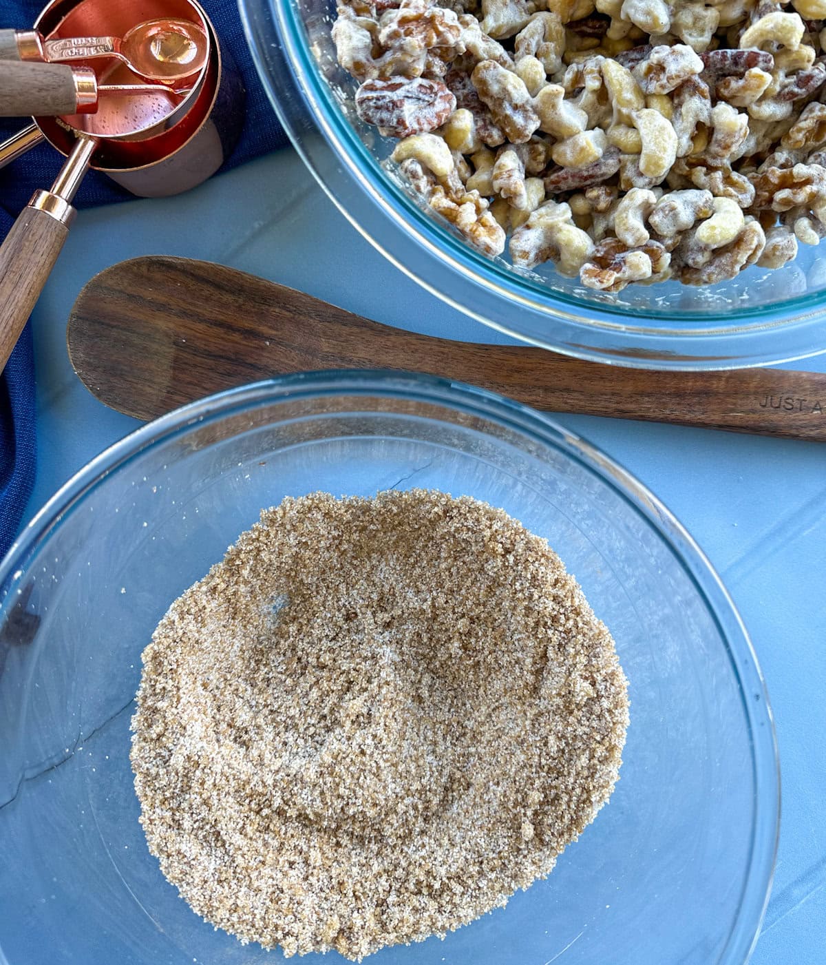 combined sugars and cinnamon in a bowl with egg white soaked nuts in the background. 