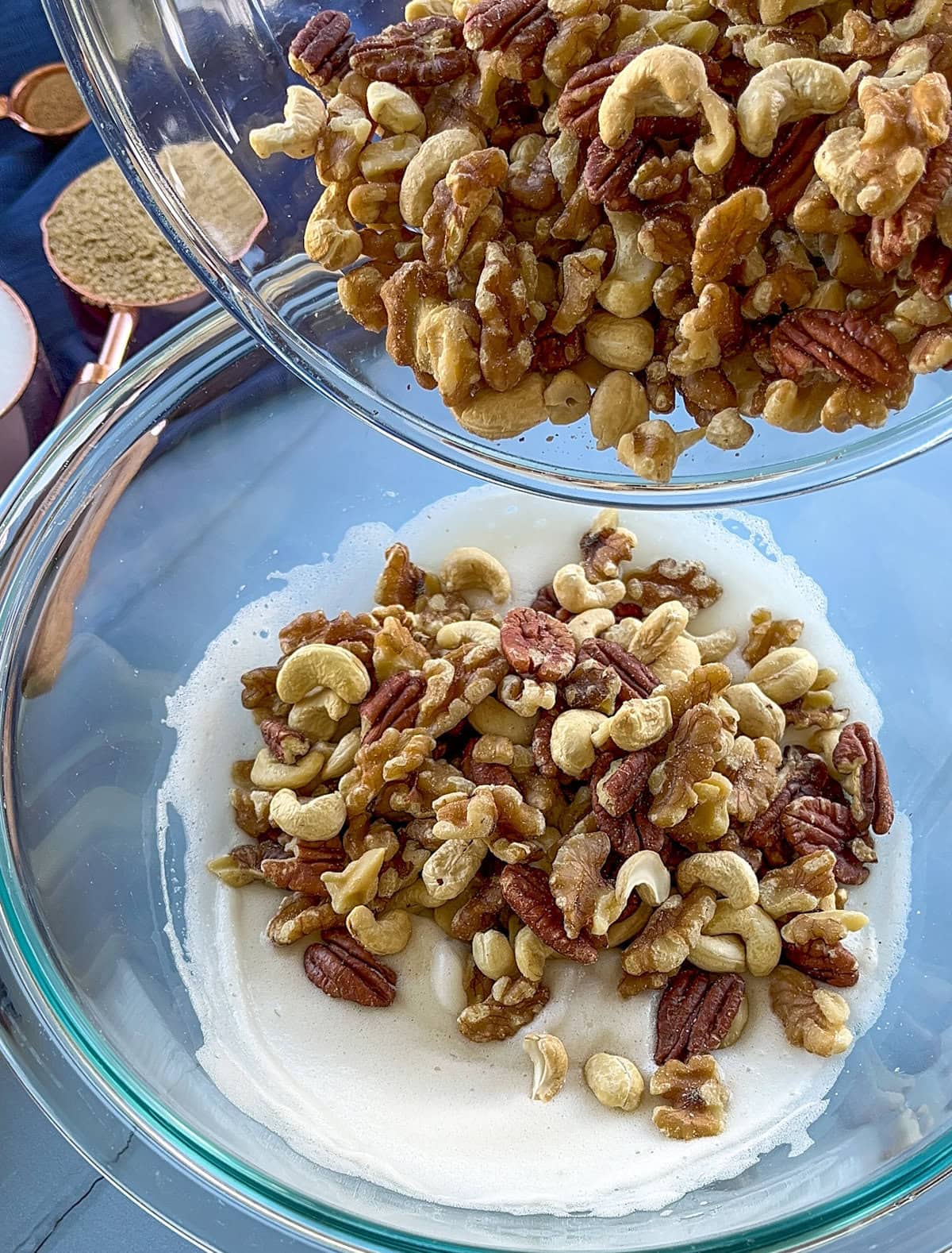 Assorted nuts being poured into the whipped egg whites to coat. 