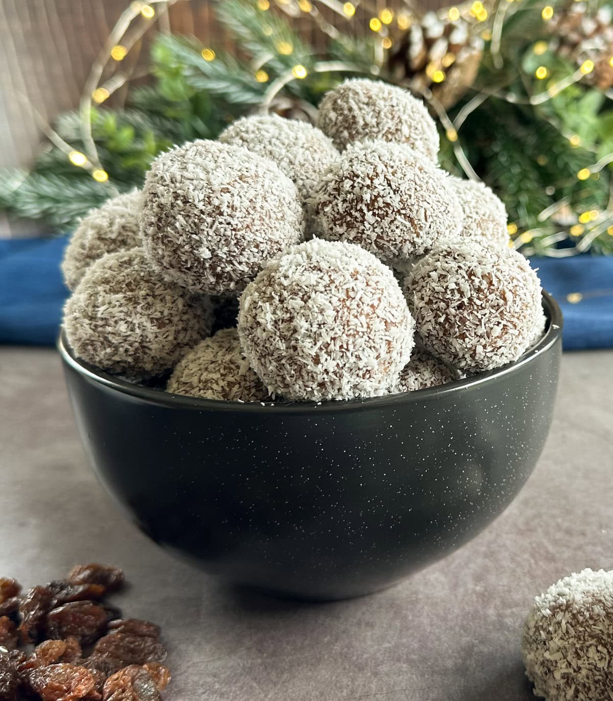 a bowl full of coconut covered rum and raisin balls 