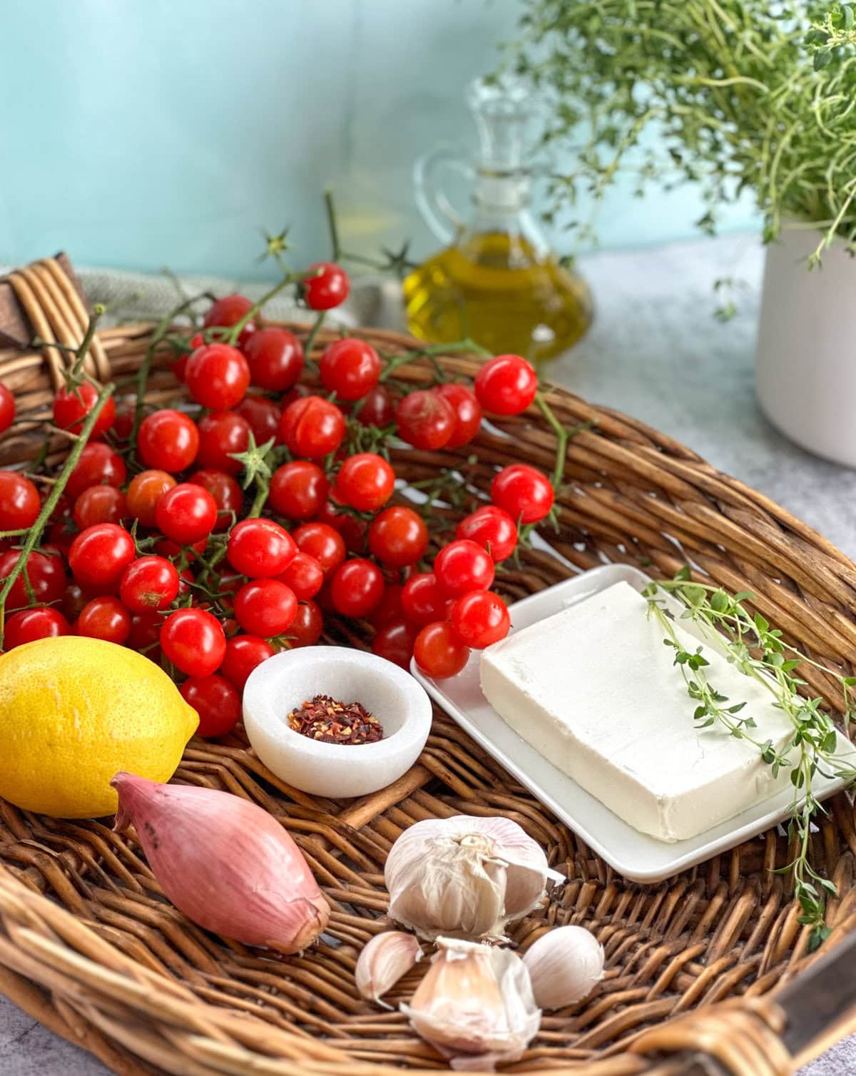 Ingredients used to make the baked feta pasta with cherry tomatoes in a large weaved basket