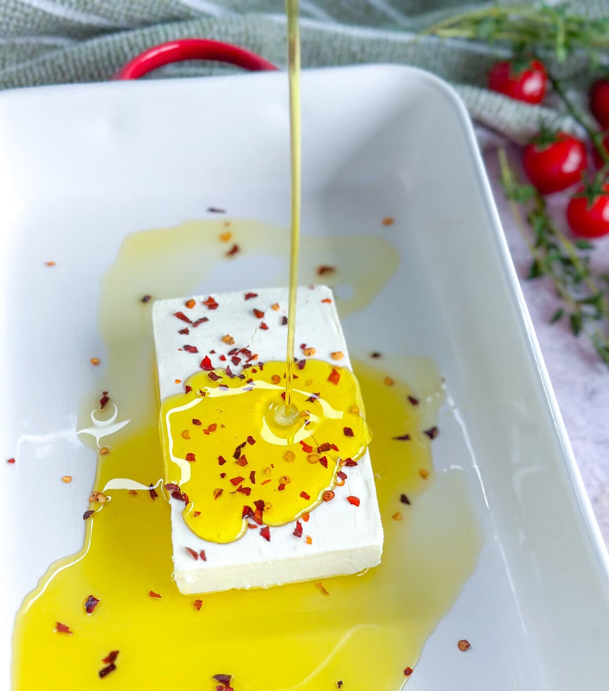 Drizzling extra virgin olive oil over feta before baking 