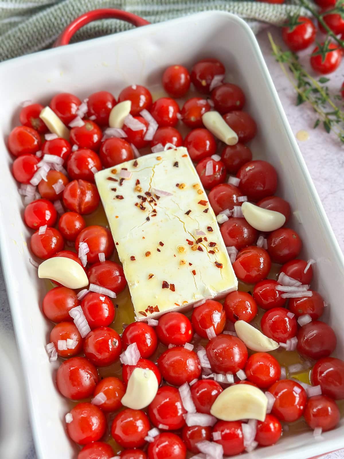 Chery tomatoes, feta, garlic and shallots in a baking dish before baking